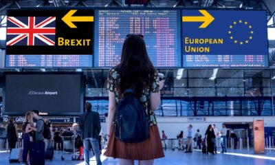 A young woman stands in an airport looking at signs