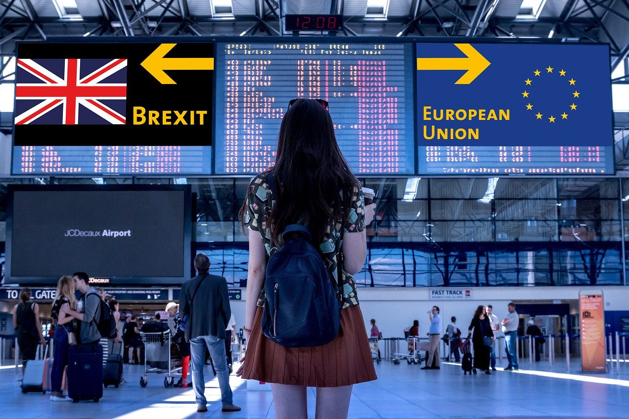 A young woman stands in an airport looking at signs