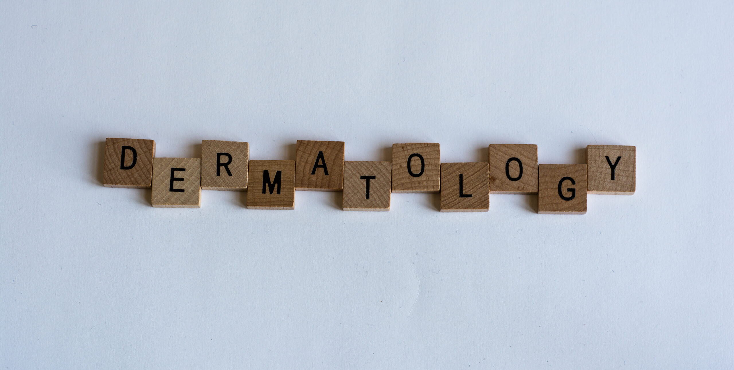 The word 'dermatology' spelled out using scrabble letters