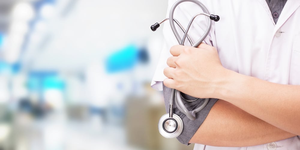 Person in white coat holding stethoscope