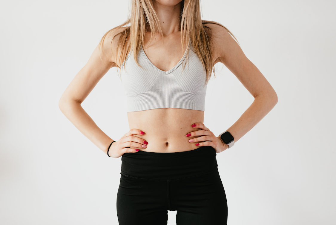 Unrecognisable woman poses in crop top and leggings