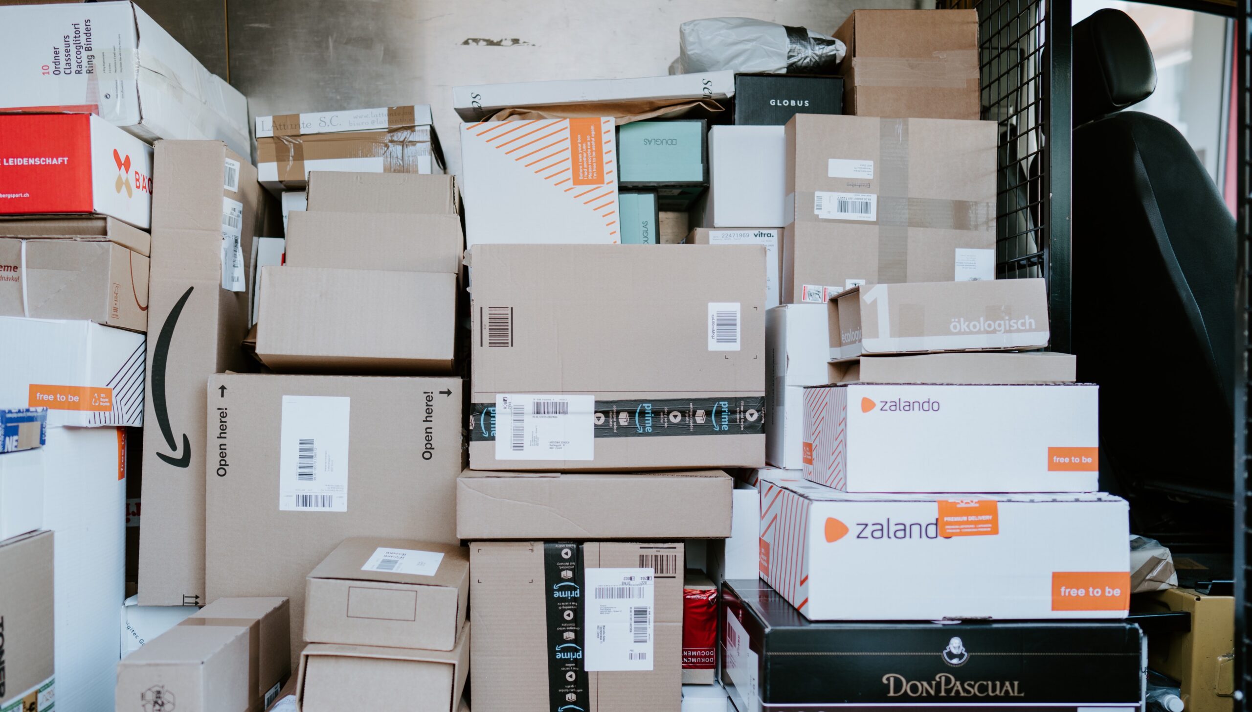 brown cardboard packages and parcels stacked in the back of a delivery van