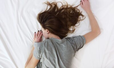 A woman lying on a white bed in pain