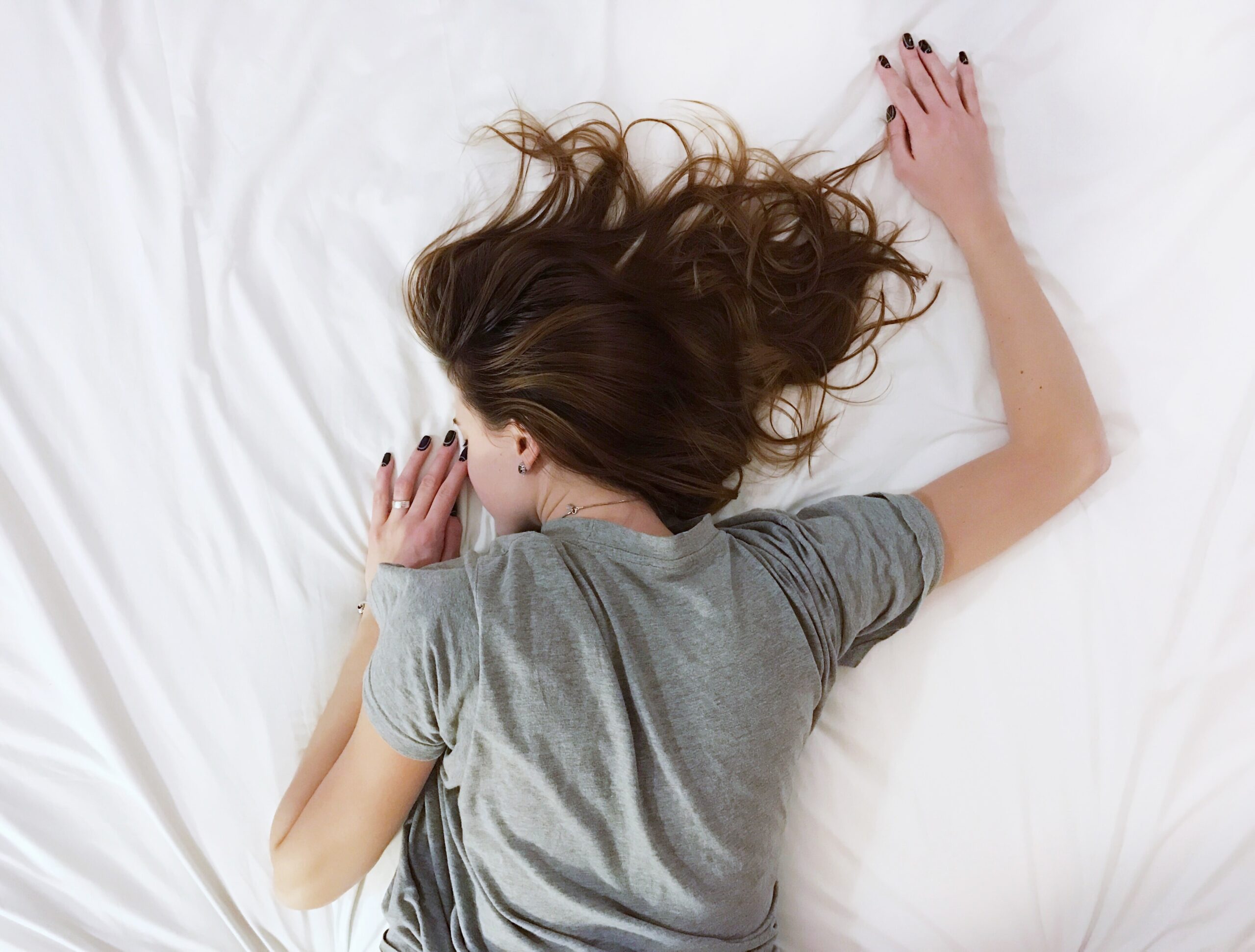 A woman lying on a white bed in pain