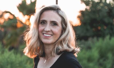 Middle aged woman with shoulder length blonde hair smiles as the sun sets behind her