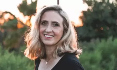 Middle aged woman with shoulder length blonde hair smiles as the sun sets behind her
