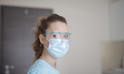 Woman wearing blue face mask and hospital scrubs looks at the camera