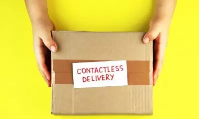 A pair of hands holds a brown parcel over a bright yellow background