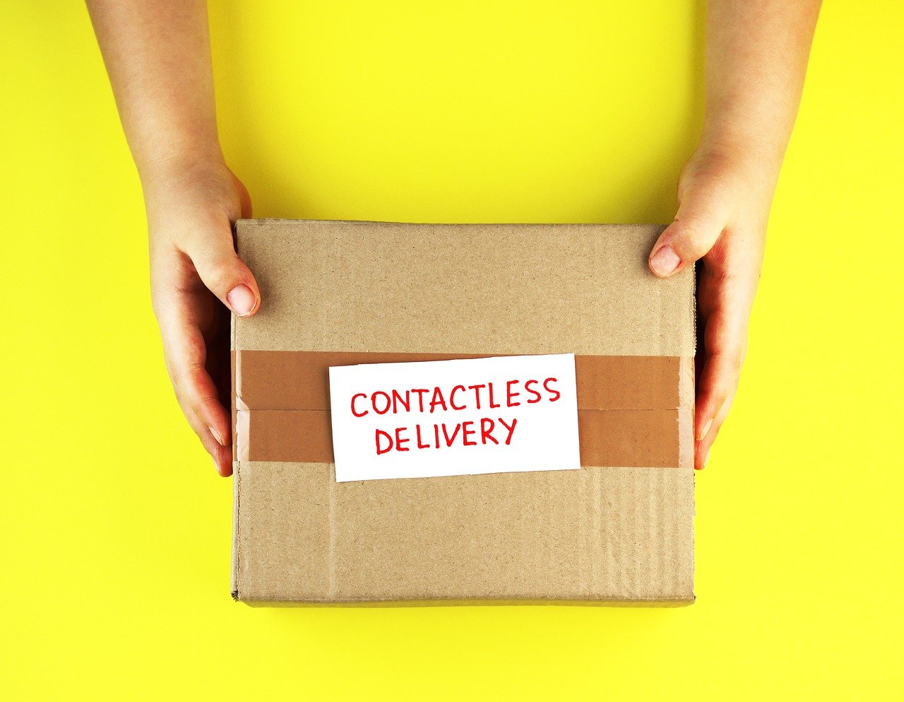 A pair of hands holds a brown parcel over a bright yellow background