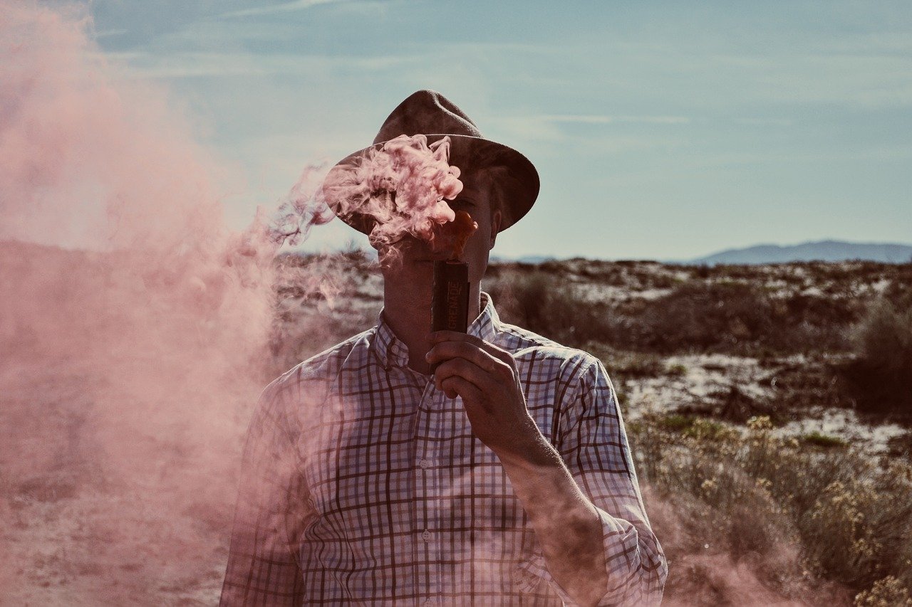 Man in checked shirt vaping outdoors