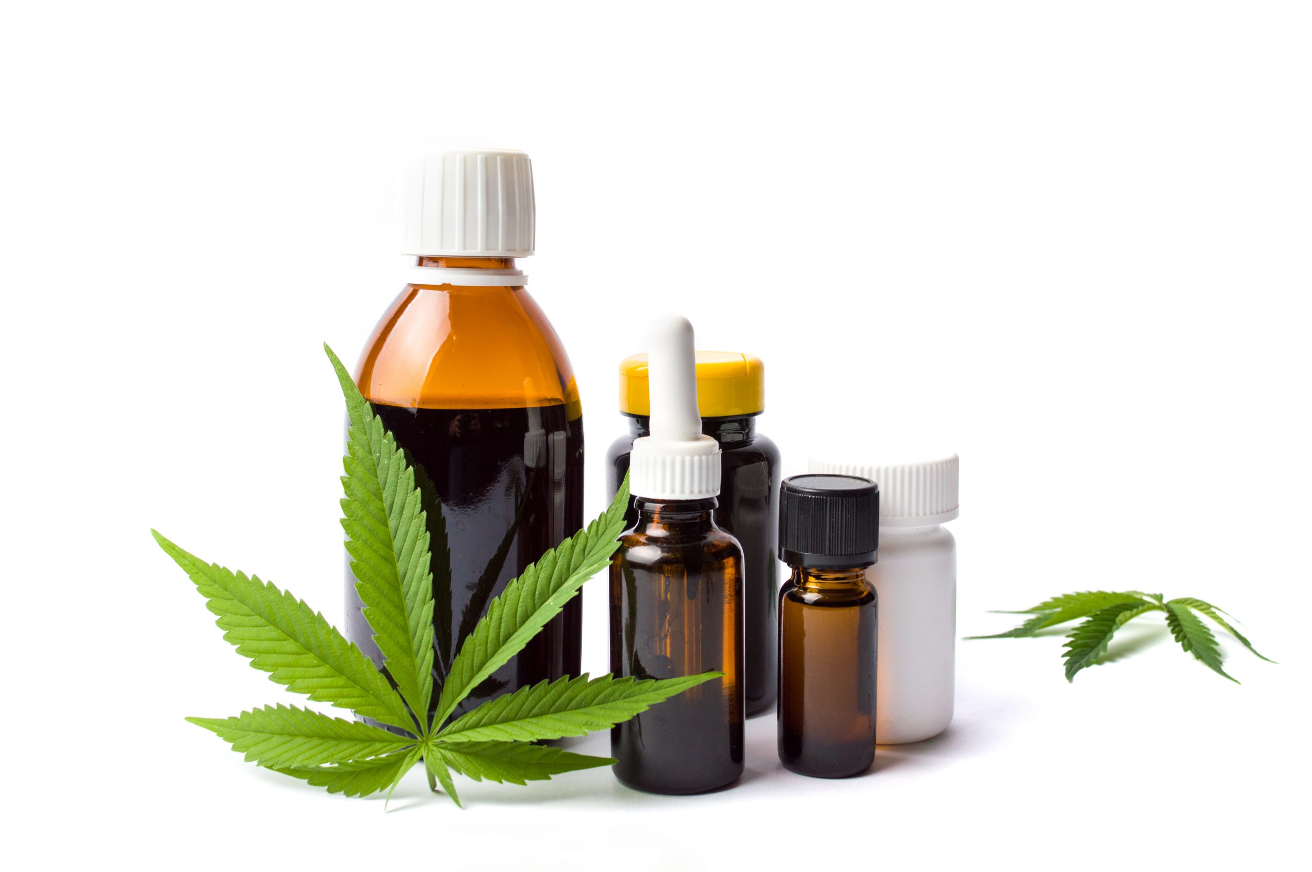 A green cannabis leaf is stood against a brown medicine bottle