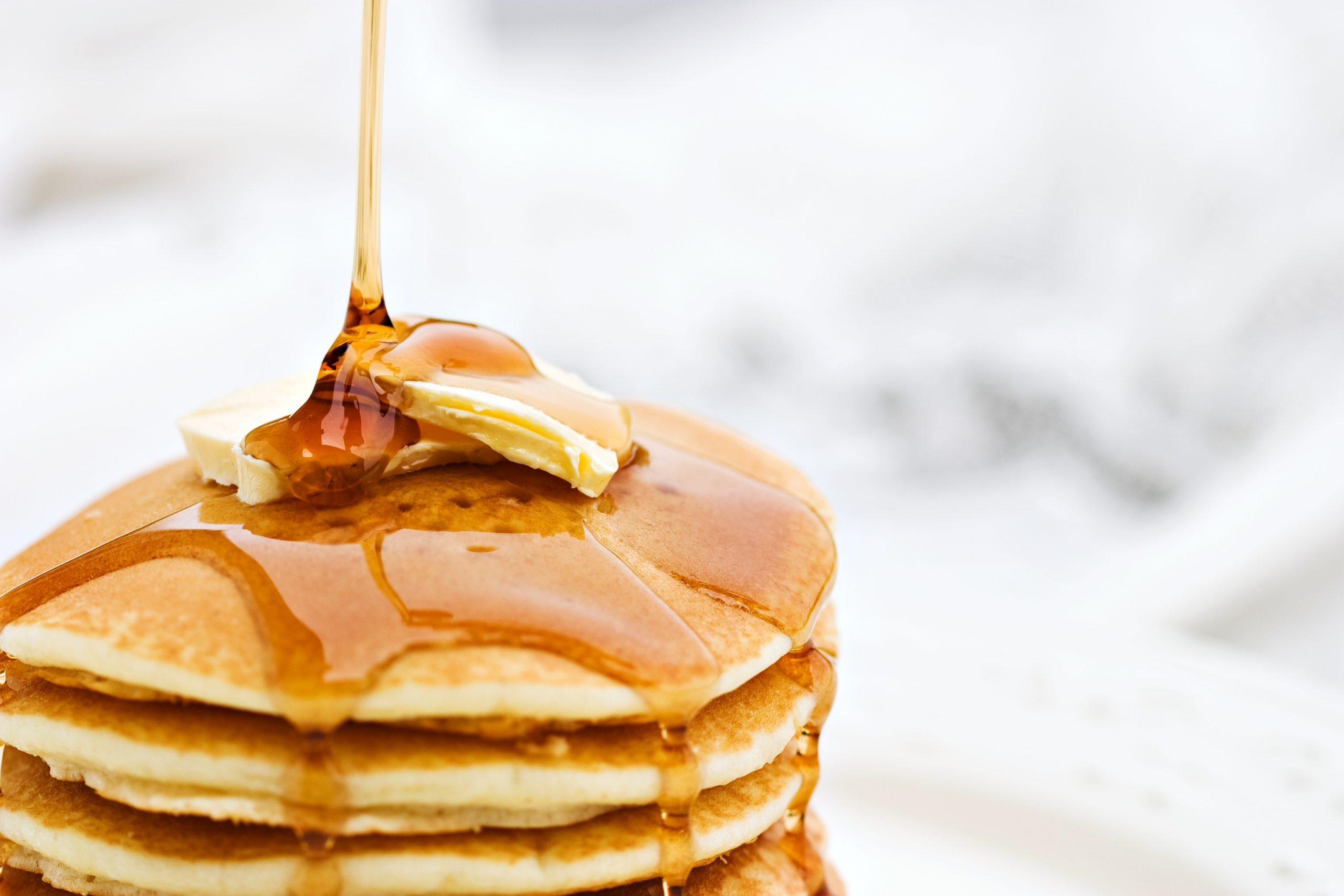 A stack of panckaes with butter and syrup.