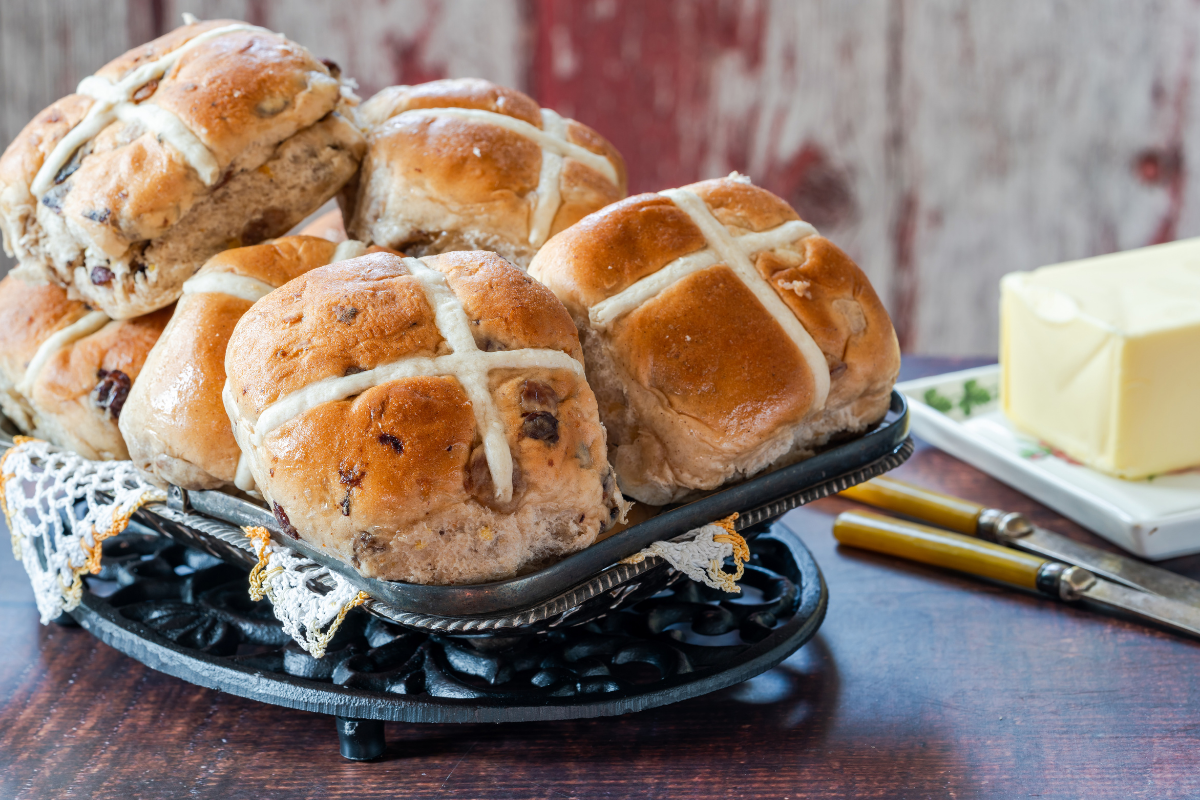 Hot Cross Buns on a plate with some butter.