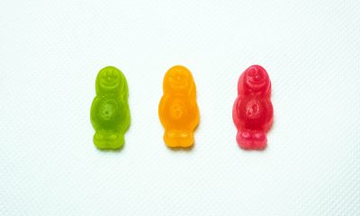 Three gummy men candies in a row on a white background