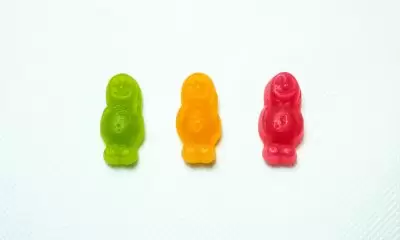 Three gummy men candies in a row on a white background