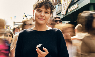 A woman holding a black vape device on a busy street