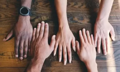Two rows of hands on a wooden table in lines