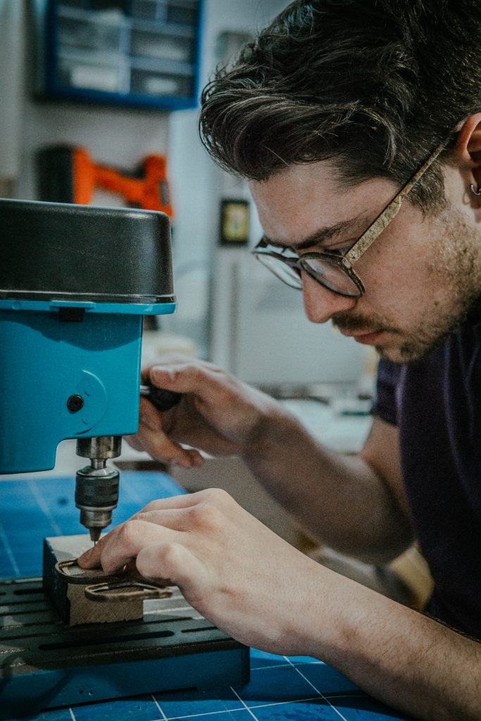 A man with dark hair and glasses is using blue machinery