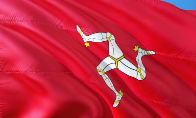 A red Isle of Man flag with three white legs against a blue sky