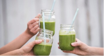 cbd-infused healthy green smoothie drinks in glass jars with straws